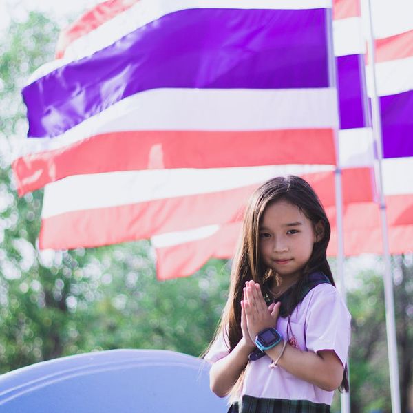 Smiling person stretching outdoors with the sun in the background.